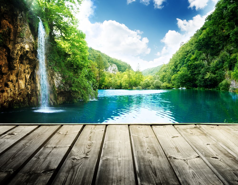 boardwalk overlooking a creek with a waterfall and lush foliage